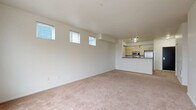 Located at 4744 12th Avenue NE in Seattle's University District, this one-bedroom, one-bathroom unit offers a well-designed, single-floor layout that makes efficient use of its space. The open-concept living, dining, and kitchen area serves as the heart of the unit, featuring plush wall-to-wall carpeting and an abundance of natural light streaming through a striking row of high clerestory windows as well as a large picture window with urban views. The kitchen is defined by a peninsula breakfast bar with a warm wood-toned countertop, light maple cabinetry, and a full suite of stainless steel appliances including a microwave, range, and refrigerator, all illuminated by track lighting overhead. The bedroom is generously proportioned, offering large windows overlooking the Seattle cityscape, soft carpeting, a dedicated closet, and a baseboard heating unit. Three closets throughout the unit provide ample storage, including a spacious walk-in fitted with wire shelving. The bathroom features wood-look vinyl flooring, a single-sink vanity with dark countertops, a full soaking tub, and the added convenience of an in-unit stacked washer and dryer. The overall aesthetic is clean and contemporary, with neutral white walls throughout.