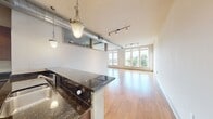 This contemporary 970 square foot apartment in Towson, Maryland offers a blend of style and functionality. The heart of the home is an open-concept kitchen and living area, featuring rich wooden cabinetry, stainless steel appliances, and a unique multi-colored slate floor. The kitchen boasts ample counter space and a convenient breakfast bar.

The living room is bathed in natural light from large windows that provide stunning city views. Gleaming hardwood floors extend throughout, adding warmth and elegance. A modern track lighting system complements the abundant natural light.

The bathroom is a study in luxury, with a double vanity, large mirror, and a separate bathtub and shower area. The multi-colored slate flooring continues here, tying the space to the kitchen's aesthetic.

A dedicated laundry room with full-sized washer and dryer adds convenience, while a walk-in closet offers generous storage. The apartment's industrial-chic vibe is accentuated by exposed ductwork in some areas.

This well-designed space maximizes every square foot, creating a home that's both stylish and practical. Its location in Towson provides easy access to urban amenities while offering a comfortable retreat from city life.