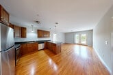 Located at 32 Carousel Ln in Lunenburg, MA, this well-appointed 2-bedroom, 2-bathroom residence offers a thoughtfully designed single-floor layout. The heart of the home is an open-concept living, dining, and kitchen area bathed in natural light, with gleaming hardwood floors flowing throughout. The kitchen is equipped with stainless steel appliances—including a refrigerator, range, microwave, and dishwasher—rich wood cabinetry, dark granite countertops, a peninsula with pendant lighting, and a sink overlooking the living space. French doors in the living area open onto a private balcony with open outdoor views, perfect for enjoying the surrounding greenery. The spacious primary bedroom features plush carpeting, a large window with natural light, and access to a generous walk-in closet with built-in shelving. The second bedroom is equally comfortable, also carpeted and featuring its own closet. Both bathrooms include wood vanities with granite countertops; one features a full tub-shower combination with tile flooring. A hallway connects all rooms, completing the functional and cohesive floor plan. This residence combines practical finishes with a warm, inviting ambiance throughout.