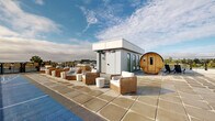 Located at 534 W Bay Terrace in Esquimalt, BC, this rooftop amenity space offers an impressive array of outdoor features designed for relaxation and recreation. The expansive rooftop terrace is finished with large-format concrete pavers and bordered by glass panel railings that preserve sweeping views of the surrounding Esquimalt neighbourhood and nearby waterfront.

A dedicated outdoor lounge area is furnished with wicker armchairs and sofas paired with white side tables, creating a comfortable gathering space for residents. Adjacent to the lounge, a full-length shuffleboard court provides a distinctive recreational feature, while a cylindrical barrel sauna adds a wellness-focused element to the terrace.

An outdoor kitchen and BBQ station, complete with a dining table and seating, makes the rooftop well-suited for entertaining. A central utility structure with glass-panelled doors connects the rooftop to the building's interior, offering convenient access. Additional lounge seating is positioned along the perimeter, taking full advantage of the open-sky exposure and distant tree-lined views.

The overall design of the rooftop balances modern, clean-lined architecture with practical amenities, making it a versatile and well-appointed outdoor space suited for both social gatherings and quiet relaxation under the open skies of Vancouver Island.