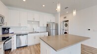 Located at 1911 Waterway Cir in Middleburg, FL, this single-story 2-bedroom, 2-bathroom home offers a clean, modern design with a bright and airy atmosphere. The open-concept living and kitchen area serves as the heart of the home, featuring light wood-look flooring, vaulted ceilings, and large windows fitted with blinds that invite abundant natural light. A front entry door with sidelights further enhances the welcoming feel of the living space.

The kitchen is well-appointed with white shaker-style cabinetry, subway tile backsplash, a center island with a neutral quartz-style countertop, stainless steel appliances including a refrigerator, dishwasher, microwave, and range, plus pendant lighting overhead. A stacked washer and dryer unit is conveniently integrated nearby.

Both bedrooms are carpeted and feature ceiling fans and windows with exterior views. The spacious primary bedroom includes a generous walk-in closet outfitted with wire shelving on multiple walls. The primary bathroom offers a dual-sink vanity with wood-framed mirrors and light wood-look flooring. The second bathroom mirrors the home's clean, minimal aesthetic with recessed lighting and quality fixtures.

A central hallway connects the rooms efficiently, completing this well-designed, move-in-ready home.