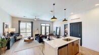 Located at 1000 North 44th Street in Phoenix, AZ, this well-appointed 2-bedroom, 2-bathroom residence offers a thoughtfully designed single-floor layout with modern finishes throughout. The open-concept living and kitchen area serves as the heart of the home, anchored by light wood-tone flooring and a seamless flow between spaces. The kitchen features warm wood cabinetry, a striking geometric tile backsplash, stainless steel appliances, and a white quartz island with seating — ideal for both cooking and casual dining. Statement pendant lighting adds a contemporary touch overhead. The living room is generously proportioned, bathed in natural light from large windows and a set of French doors that open to an outdoor balcony, offering views of the surrounding Phoenix landscape. Ceiling fans in both the living area and bedrooms enhance comfort year-round. Each bedroom offers plush carpet, natural light through large windows, and ceiling fans, with the primary bedroom featuring its own closet with built-in shelving. The bathrooms are finished with wood-toned vanities, white quartz countertops, framed mirrors, and combination tub-shower setups. Two dedicated closets provide ample storage throughout this well-balanced and stylish Phoenix residence.