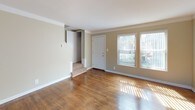 This two-floor residence offers a well-organized layout designed for comfortable everyday living. The main level greets visitors with a bright, open living area showcasing rich hardwood flooring that extends throughout. Natural light streams in through large windows dressed with vertical blinds, illuminating the warm neutral tones of the walls and the clean white trim and crown molding that frame each room. A staircase connects the main level to the upper floor, with a convenient coat closet nearby at the entry.

The kitchen is efficiently laid out with white cabinetry providing ample storage, a gas range, a full-size refrigerator, and a window above the sink that brings in additional natural light. Tile flooring completes the practical design of this space.

Upstairs, the bedrooms are generously sized and carpeted, each featuring crown molding, ceiling-mounted light fixtures, and windows that allow plenty of daylight. One bedroom includes direct access to a bathroom, enhancing its functionality. A full bathroom on this level is neatly appointed with tile flooring, a vanity with mirror, and a narrow window for ventilation and light.

A standout feature is a spacious room with gleaming hardwood floors, a ceiling fan, and a full wall of mirrored closet doors that amplify the sense of space and light, making it a versatile and airy retreat.