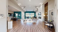 Located at 100 Spadeleaf Boulevard in Hendersonville, Tennessee, this single-story community space offers a well-appointed and generously sized layout across one open floor. Warm hardwood-style flooring flows throughout, creating a cohesive and inviting atmosphere.

The combined kitchen and living room serves as the heart of the space. The kitchen features dark espresso cabinetry, a mosaic tile backsplash, stainless steel appliances including a French door refrigerator and built-in microwave, a white quartz-topped island with pendant lighting above, and bold teal accent walls that add a vibrant pop of color. The adjoining living area is anchored by a wall-mounted fireplace with a sleek surround, a large flat-screen TV, and generous seating arrangements beneath soaring ceilings with recessed lighting and ceiling fans. Tall, floor-to-ceiling windows flood the room with natural light while offering views to the outdoors, and a built-in bar-height workstation provides a functional workspace.

The game room is a standout recreational feature, centered around a classic billiards table beneath a stained-glass hanging light fixture, complemented by additional seating and billiards-themed wall art. A connecting hallway links the areas seamlessly, completing this dynamic and multifunctional community space.