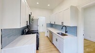 Located at 601 W Cliveden St in Philadelphia's Mt. Airy neighborhood, this single-floor, 2-bedroom, 2-bathroom unit offers a thoughtfully updated interior with a clean, modern aesthetic throughout. Light wood laminate flooring runs continuously across all living areas, complementing the crisp white walls and recessed lighting that brighten each room.

The galley-style kitchen is well-appointed with white shaker cabinetry, light-colored countertops, a powder-blue subway tile backsplash, and stainless steel appliances including a gas range, microwave, and refrigerator. A door off the kitchen leads to a private balcony with sweeping views of mature trees and the surrounding greenery.

The spacious primary bedroom features a double window overlooking lush tree canopy, a classic cast-iron radiator, and recessed lighting. The second bedroom is also generously sized with its own window and radiator. Both rooms offer a clean, neutral palette suited for a variety of configurations. Each bathroom is finished with a white vanity, black-framed mirror, and black fixtures, lending a contemporary contrast to the otherwise light interior.

The living room connects openly to the hallway layout and receives natural light through a side-facing window. Three hallways provide practical circulation throughout the unit, and the overall layout is efficient and functional.