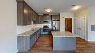 This thoughtfully designed one-bedroom, one-bathroom residence at 321 S Broad St in Elizabeth, NJ offers a well-organized single-floor layout with modern finishes throughout. The kitchen is a standout feature, showcasing rich dark cabinetry, granite countertops, a classic white subway tile backsplash, and a full suite of stainless steel appliances including a gas range, microwave, dishwasher, and refrigerator with ice maker. A kitchen island provides additional prep and counter space, while wood-style flooring ties the kitchen seamlessly into the open living area, which is brightened by a window and flush-mount ceiling lighting. The bedroom offers plush carpeting, neutral-toned walls, and a generous window that invites natural light and views of the surrounding neighborhood. The full bathroom is finished with large-format tile flooring, a tiled tub-surround with soaking tub, a dark-cabinetry vanity with white countertop, and a well-lit mirror. A stacked in-unit washer and dryer adds everyday convenience. Clean lines, neutral tones, and contemporary fixtures create a cohesive and inviting atmosphere throughout this move-in-ready home.