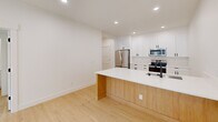 Located at 4969 S Freya St in Spokane, WA, this thoughtfully designed unit offers four bedrooms and two bathrooms across a single floor. The interior features light hardwood flooring throughout, crisp white walls, and recessed lighting that create a clean, modern aesthetic.

The kitchen is a standout feature, showcasing white shaker cabinetry with matte black hardware, quartz countertops, stainless steel appliances including a refrigerator, electric range, and microwave, as well as a peninsula with a natural wood base — ideal for casual dining or additional workspace. A matte black faucet and undermount sink complete the polished look.

The four bedrooms are bright and well-proportioned, each benefiting from natural light through sliding or casement windows with views of the surrounding landscape. Select bedrooms include sliding panel closets and wall-mounted mini-split HVAC units for individual climate control. Shaker-style interior doors maintain a cohesive design language throughout.

The two bathrooms are finished with white cabinetry, quartz vanities, matte black fixtures, and framed mirrors. One bathroom features a tub-shower combo with dark hardware, while the other offers a windowed layout for added natural light. Three hallways connect the space efficiently, rounding out this well-appointed and move-in ready unit.