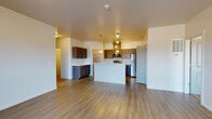 Located at 3698 East Hope Avenue in Post Falls, Idaho, this single-floor residence offers a thoughtfully designed open-concept layout that seamlessly connects the kitchen, dining, and living areas. The main living space features durable wood-look plank flooring that flows throughout the common areas, complemented by neutral-toned walls and textured ceilings that lend a clean, modern aesthetic.

The kitchen is a functional centerpiece, equipped with stainless steel appliances including a refrigerator, electric range, and over-the-range microwave. Rich dark-toned cabinetry with sleek hardware contrasts attractively against light countertops. A central kitchen island with pendant lighting overhead provides additional prep space and a natural gathering point. Track lighting further enhances the kitchen's illumination. A walk-in pantry offers generous storage.

The living room is open and airy, benefiting from natural light through sliding windows that frame views of the surrounding landscape. Bedroom spaces are finished with plush carpet flooring and feature windows that invite additional natural light and outdoor views.

The bathrooms are finished consistently with wood-look plank flooring, dark-cabinetry vanities with light countertops, and full tub-shower combinations with chrome fixtures. The overall design prioritizes a clean, contemporary feel throughout the entire single-level floor plan.
