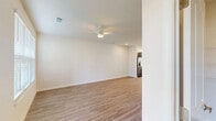 This well-designed two-story home offers 3 bedrooms and 3 bathrooms across two thoughtfully laid-out floors. The main level features an open-concept living, dining, and kitchen area finished with light wood-look flooring and crisp white walls, creating a bright and airy atmosphere. A ceiling fan anchors the living space, while recessed lighting adds a modern touch. The kitchen is equipped with stainless steel appliances, including a range, microwave, and dishwasher, complemented by grey shaker-style cabinetry, white countertops, and a single-basin sink beneath a window that allows natural light to flow in. A staircase with carpeted treads leads to the upper floor, where the three bedrooms are located. The spacious primary bedroom features plush carpeting and direct access to an en-suite bathroom. The additional bedrooms are similarly carpeted and well-proportioned. The bathrooms are finished with grey vanities, white countertops, and tub-shower combinations. Seven closets provide generous storage throughout. An attached garage with an automatic opener adds convenience. The exterior showcases a charming stone veneer facade, a concrete driveway, and neatly landscaped front beds with mature shrubs.