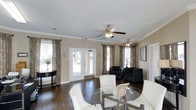 This single-floor leasing office is thoughtfully designed to create a warm and professional atmosphere for visitors and prospective residents alike. Rich, dark hardwood flooring runs throughout the main area, providing a polished foundation that complements the neutral wall tones and crisp white crown molding that frames the space with a refined architectural detail.

The main reception and seating area is generously proportioned, featuring a glass-top table surrounded by white chairs, ideal for consultations or informal meetings. A separate lounge-style seating arrangement with dark upholstered armchairs offers an additional area for relaxed conversation. Ceiling fans with integrated lighting fixtures are positioned throughout, ensuring comfort and ambient illumination.

Large windows dressed in decorative patterned curtains allow natural light to flood the interior, while a set of full-length French doors leads directly to the exterior, further enhancing the bright and open feel of the space. Tasteful wall art and accent furnishings complete the inviting aesthetic. The textured ceiling adds subtle visual character overhead. Overall, the leasing office balances approachability with professionalism, making it a welcoming first point of contact for the community it serves.