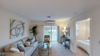 This single-floor residence offers a thoughtfully designed layout that balances comfort and functionality across its key living spaces. The living room serves as the heart of the home, finished with plush carpeting and neutral warm tones on the walls. A large sliding glass door floods the space with natural light and provides direct access to an outdoor balcony, while a wall-mounted mini-split unit ensures year-round climate comfort.

The kitchen is well-equipped for everyday living, featuring rich dark-wood cabinetry, granite-toned countertops, and a full suite of stainless steel appliances including a range, microwave, refrigerator, and dishwasher. Stone-look tile flooring and generous cabinet storage add both practicality and visual appeal.

The primary bedroom is a calm, carpeted retreat with windows dressed in horizontal blinds that filter soft natural light. A second bedroom offers similar finishes and comfortable proportions, making it well-suited as a guest room or home office. The full bathroom includes a wood-toned vanity, a glass-enclosed shower, stone-look tile flooring, and accessibility-friendly fixtures, rounding out a space designed with both style and convenience in mind.