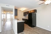 This single-floor residence offers a thoughtfully designed layout that balances comfort and functionality. The entryway greets visitors with wood-look plank flooring and a coat closet, opening seamlessly into the main living area. The living and dining spaces flow naturally together, with soft carpet underfoot, a ceiling fan, and access to natural light through a large window with vertical blinds.

The galley-style kitchen is a standout feature, lined on both sides with rich, dark espresso cabinetry accented by brushed chrome hardware and a decorative tile backsplash. Granite-style countertops provide ample workspace, and the kitchen is equipped with black appliances including a range, microwave, refrigerator, and a sink with a modern faucet. Wood-look flooring continues throughout this space, adding warmth and cohesion.

The two bedrooms are generously sized, each featuring plush wall-to-wall carpet, neutral warm-toned walls, sliding double-door closets, and windows that invite natural light. The textured ceilings add a classic touch throughout the home.

Both bathrooms are clean and functional, featuring wood-look tile flooring, dark vanity cabinetry with granite-style countertops, and a tub-shower combination with white subway-style tile surround. The overall ambiance is neutral, bright, and move-in ready.