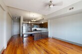 Located in the heart of New Orleans at 427 Josephine St, this one-bedroom, one-bathroom residence blends historic character with modern finishes. Rich, wide-plank hardwood floors in warm amber tones flow throughout the entire space, creating a cohesive and inviting atmosphere. The open kitchen and living area serves as the heart of the home, where the kitchen stands out with dark espresso cabinetry, granite countertops, stainless steel appliances, and a peninsula with a double sink — ideal for both cooking and casual dining. Pendant lighting above the peninsula adds a contemporary touch. The bedroom is a standout space, distinguished by an exposed brick wall with an arched window detail that allows natural light to pour in, evoking the classic architectural character of New Orleans. The bedroom also features a mirrored closet and direct access to the bathroom. The bathroom is finished with classic black-and-white mosaic tile flooring, a tub-shower combination, white cabinetry, and granite countertops. Neutral gray walls throughout the unit provide a clean, modern backdrop that complements the historic details, resulting in a space that feels both timeless and move-in ready.