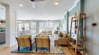 Located at 655 W Mallard Creek Church Rd in Charlotte, NC, this single-floor community space offers a thoughtfully designed environment that blends comfort and functionality. The interior is unified by a calming coastal color scheme, featuring soft sage and teal accent walls complemented by warm wood-look tile flooring and crisp white crown molding throughout.

The main lounge area is generously proportioned, furnished with plush neutral sofas, patterned accent chairs, and layered area rugs in rich teal and blue tones. Vibrant abstract artwork and decorative shelving add personality to the walls, while a ceiling fan and recessed lighting ensure year-round comfort. Expansive French doors and large windows fitted with plantation shutters flood the space with natural light and provide views of the outdoor surroundings.

A dedicated dining nook accommodates a round wooden table with upholstered curved chairs, bathed in natural light from multiple windows — ideal for small gatherings or meetings.

The kitchen features a long granite countertop with bar-height seating for several guests, white shaker-style cabinetry, stainless steel appliances, and pendant lighting, making it well-suited for social events. Together, these areas create an inviting, versatile community hub with a polished yet relaxed aesthetic.