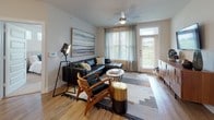 This single-floor residence offers a thoughtfully designed layout that balances comfort and modern style. The open-concept living area is anchored by large windows and a glass door that invite abundant natural light and provide views of the surrounding greenery. A ceiling fan adds a functional touch, while light wood flooring flows throughout the space, lending warmth and visual continuity.

The kitchen is equipped with dark espresso cabinetry, stainless steel appliances including a range, over-the-range microwave, and refrigerator, all complemented by crisp white quartz countertops and a large island with an undermount sink. Ample storage is provided by full-height upper cabinets and a double-door pantry closet.

The residence includes multiple bedrooms, each featuring plush carpeting, generous windows with blinds and draping curtains, and a ceiling fan for comfort. The primary bedroom connects to a spacious en-suite bathroom with a long double-vanity, dark cabinetry, white countertops, and wood-look flooring. A second full bathroom mirrors this refined aesthetic with a single vanity and matching finishes.

Throughout the home, neutral gray walls, clean white millwork, and cohesive wood-tone accents create a contemporary and inviting atmosphere well-suited for everyday living.