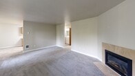 Located at 7412-7416 Golden Given Rd E, Unit 13 in Tacoma, WA, this two-bedroom, two-bathroom residence offers a practical and comfortable single-floor layout. The spacious living room serves as the focal point of the home, featuring plush gray carpeting, neutral-toned walls, and a tile-surround fireplace that adds warmth and character. A window with vertical blinds allows natural light to fill the room, and a dedicated laundry area is conveniently accessible from the living space. The galley-style kitchen is well-equipped with warm wood cabinetry lining both walls, light countertops, tile flooring, and white appliances including an electric range, refrigerator, and dishwasher. Ample cabinet storage makes the kitchen both functional and organized. Both bedrooms are carpeted and feature neutral walls, with the primary bedroom offering a sliding-door closet and a window overlooking the outdoors. Each bedroom is served by its own bathroom, both finished with wood-toned vanity cabinetry, light countertops, and tile flooring. Throughout the unit, warm wood-toned doors and trim create a cohesive, inviting aesthetic. This well-laid-out residence offers a comfortable living experience in a convenient Tacoma location.