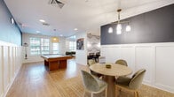 This 640 square foot single-story space in Glen Allen, VA, showcases a contemporary design that maximizes functionality. The open-plan layout seamlessly integrates living, dining, and work areas. The living room features a comfortable L-shaped sofa positioned near large windows, offering natural light and views of the surrounding area. A stylish round dining table with upholstered chairs creates an inviting eating space, illuminated by a modern three-light pendant fixture.

The office area is equipped with a built-in wooden desk, providing a dedicated workspace. Throughout the space, hardwood flooring adds warmth and continuity. The walls combine neutral tones with accent colors, including a striking dark accent wall in the dining area complemented by white wainscoting. The ceiling in the living area features white planks, adding texture and visual interest.

Thoughtful lighting solutions, including recessed lights and a ceiling fan, enhance the ambiance. The space also includes entertainment options, with a mounted TV and a pool table for leisure activities. Overall, this compact yet well-designed space offers a balanced blend of comfort, style, and practicality for modern living and working.
