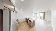 Located on the seventh floor at 601 E Pike St in Seattle's Capitol Hill neighborhood, Unit 707 is a modern residential unit designed with a clean, contemporary aesthetic throughout. The open-concept living and kitchen area serves as the heart of the home, featuring light wood-tone flooring, soaring ceilings, and an abundance of natural light streaming through floor-to-ceiling windows framed in warm wood tones. These expansive windows offer impressive views of the Seattle cityscape and open onto a private balcony, seamlessly blending indoor and outdoor living.

The kitchen is equipped with a full suite of stainless steel appliances, including a refrigerator, electric range, over-the-range microwave, and dishwasher. Rich dark cabinetry pairs with light quartz-style countertops and a classic subway tile backsplash, creating an elegant and functional cooking space. A peninsula island with a dual-basin sink and additional storage adds to the kitchen's practicality.

The bedroom is generously proportioned with a large picture window overlooking the urban landscape and features a sliding-door closet offering ample storage. The bathroom is well-appointed with a dark vanity, vessel-style sink, light stone countertop, and a full soaker tub with a shower, all set against crisp white walls and matching wood-tone flooring that unifies the space throughout.