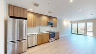 Located on Lamont Street Northwest in Washington, DC, this 1-bedroom, 1-bathroom unit offers a thoughtfully designed layout with modern finishes throughout. Light hardwood flooring flows seamlessly across the open living and kitchen areas, creating a cohesive and airy feel.

The kitchen is a standout feature, showcasing flat-front wood-grain cabinetry that extends to the ceiling, white quartz countertops, a white tile mosaic backsplash, and a full suite of stainless steel appliances including a refrigerator, dishwasher, range, and microwave. A floor-to-ceiling window at the end of the living area draws in natural light and provides views of the surrounding neighborhood.

The bedroom is a comfortable, well-proportioned space with light hardwood flooring, neutral warm-toned walls, and a window with outdoor tree views. A hallway connects the bedroom to the bathroom, closet, and pantry, keeping the space organized and functional.

The bathroom features a tub-shower combination with classic white subway tile surround, a wood-grain vanity with a white countertop, a large mirror, and neutral tile flooring. A dedicated closet and pantry provide ample storage. Recessed lighting throughout completes this clean, contemporary residence.