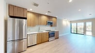Located on Lamont Street Northwest in Washington, DC, this 1-bedroom, 1-bathroom unit offers a thoughtfully designed layout with modern finishes throughout. Light hardwood flooring flows seamlessly across the open living and kitchen areas, creating a cohesive and airy feel.

The kitchen is a standout feature, showcasing flat-front wood-grain cabinetry that extends to the ceiling, white quartz countertops, a white tile mosaic backsplash, and a full suite of stainless steel appliances including a refrigerator, dishwasher, range, and microwave. A floor-to-ceiling window at the end of the living area draws in natural light and provides views of the surrounding neighborhood.

The bedroom is a comfortable, well-proportioned space with light hardwood flooring, neutral warm-toned walls, and a window with outdoor tree views. A hallway connects the bedroom to the bathroom, closet, and pantry, keeping the space organized and functional.

The bathroom features a tub-shower combination with classic white subway tile surround, a wood-grain vanity with a white countertop, a large mirror, and neutral tile flooring. A dedicated closet and pantry provide ample storage. Recessed lighting throughout completes this clean, contemporary residence.