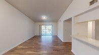This two-bedroom, two-bathroom single-floor residence in Sunrise, Florida offers a well-organized layout designed for comfortable everyday living. The open-concept living room is a standout space, featuring soaring vaulted ceilings that amplify the sense of space, durable wood-look flooring, and a sliding glass door that leads to a private balcony with lush outdoor views. A pass-through window connects the living area to the kitchen, which is equipped with white cabinetry, a refrigerator, and a range, creating an efficient and functional cooking space with an adjacent pantry closet. The spacious primary bedroom features soft carpeting, a textured ceiling, and access to a generous walk-in closet outfitted with wire shelving for ample storage. The second bedroom is similarly carpeted and well-proportioned, with a door connecting to the hallway. Both bathrooms are clean and functional, with one featuring a full tub-shower combo, white tile surround, and terracotta tile flooring alongside a vanity with counter space. Throughout, the residence maintains a bright, neutral palette with white walls and trim that enhance the natural light flowing through the space. A dedicated hallway connects all rooms, contributing to a logical and comfortable floor plan.