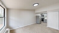 Located at 5500 St Marys Rd in Columbus, Georgia, this single-floor unit offers a thoughtfully arranged layout comprising a living room, kitchen, and bathroom. The living area is finished with neutral-toned carpet and clean white walls, creating a bright and understated atmosphere. A large window with a black frame allows natural light to filter in, offering a view of the surrounding outdoor greenery, while a wall-mounted HVAC unit ensures year-round climate control. A flush-mount ceiling light fixture provides consistent overhead illumination throughout the space. The kitchen is efficiently designed and features stainless steel appliances, including a full-size refrigerator, an electric range, and an over-the-range microwave. Gray shaker-style cabinetry lines the walls, complemented by a white countertop, a single-basin sink, and a subway tile backsplash. Light wood-look flooring grounds the kitchen area, providing a clean contrast to the soft carpeting in the living space. The bathroom maintains a simple, clean aesthetic with wood-look tile flooring, white fixtures, and a towel bar, keeping the overall feel consistent with the rest of the unit. Together, these spaces form a functional and well-maintained layout suited for efficient, comfortable living.