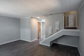 Located at 811 S Sullivan St in Santa Ana, California, this two-story residence offers a thoughtfully updated interior with contemporary finishes throughout. The main living area welcomes you with durable wood-look flooring, soft neutral gray walls, and a textured ceiling, creating a clean and versatile backdrop. A sliding glass door floods the space with natural light while providing a view of the surrounding greenery, and a traditional front door with a decorative half-moon window adds classic curb appeal.

The staircase connecting both floors is a standout architectural feature, showcasing ornate white laser-cut floral panel railings that add a distinctive decorative touch against the neutral palette. Wood-look flooring continues throughout both levels for a cohesive look.

The kitchen is well-appointed with light wood cabinetry, white countertops, a stainless steel farmhouse sink with a matte black faucet, and a stainless steel range. A sliding glass door and window bring in ample natural light, making the space bright and functional.

The bathroom features a double-sink vanity with warm wood cabinetry, white countertops, dual undermount sinks, and matte black fixtures, all illuminated by a sleek modern light bar above a large mirror — a clean and practical design that elevates the everyday experience.
