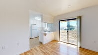Located in Encinitas, California, this two-bedroom, one-bathroom unit offers a well-organized single-level layout filled with natural light. The open living area features warm hardwood-style flooring and connects seamlessly to a private balcony through sliding glass doors, offering pleasant outdoor views of the surrounding neighborhood and greenery. The kitchen is efficiently designed with white cabinetry, tile countertops, a peninsula breakfast bar, and tile flooring. Ample cabinet storage, a full-size refrigerator, dishwasher, and a window above the sink enhance the kitchen's functionality. The primary bedroom is a comfortable size, featuring hardwood-style flooring, a window with vertical blinds for natural light and privacy, and access to additional storage. The second bedroom also showcases hardwood-style floors, a window, and built-in cabinetry, adding useful storage space. The bathroom has been thoughtfully updated with large-format marble-style wall tiles, a mosaic accent border, a walk-in shower with a white basin, and brushed nickel grab bars. Tile flooring carries through the wet areas of the unit. Clean white walls throughout contribute to a bright, airy ambiance, making this Encinitas unit a practical and comfortable coastal California residence.