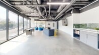 Located at 355 Glendale Blvd in the Echo Park neighborhood of Los Angeles, this single-floor amenity lounge offers a generously sized, open-plan layout with a distinctly modern industrial aesthetic. The space features exposed ductwork and structural elements overhead, complemented by sleek linear pendant lighting that illuminates the polished concrete floors below.

The layout is divided into two interconnected zones. The first is a social lounge area furnished with contemporary blue modular sofas, round pod-style chairs, and a glass-top coffee table, creating an inviting gathering space. A wall-mounted display screen and vibrant artwork add personality to the clean white walls. A shuffleboard table provides additional entertainment options. The second zone transitions into a recreation and casual retreat area, centered around a full-size billiards table. A leather sofa nearby offers a relaxed seating option, while a kitchenette with green subway tile backsplash, counter seating, and open shelving serves as a functional refreshment hub.

Floor-to-ceiling windows span the street-facing wall, flooding the entire space with abundant natural light and offering open views of the surrounding Los Angeles streetscape. The result is a bright, versatile, and energetic communal environment well-suited for socializing and recreation.