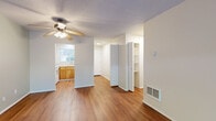 This well-organized 2-bedroom, 1-bathroom single-floor home offers a practical and comfortable layout across a compact yet efficient footprint. The living room serves as the heart of the space, featuring warm hardwood flooring, a ceiling fan with light fixture, and a large sliding glass door that floods the room with natural light while offering pleasant views of lush outdoor greenery. The kitchen is efficiently designed in a U-shaped configuration, outfitted with warm wood cabinetry, white appliances including a range and refrigerator, a double-basin sink, and a window that brings in additional natural light. Built-in shelving in the hallway area provides convenient storage. The primary bedroom is a generously sized retreat featuring hardwood floors, a ceiling fan, and an accent wall painted in a soothing teal tone. It is complemented by a spacious closet with a full-width hanging rod. The second bedroom offers soft carpeting, a window with a garden view, and its own closet. Both bedrooms connect through a central hallway. The shared bathroom is well-appointed with a granite-topped vanity with rich wood cabinetry, a tub-shower combination with sliding glass doors, and tile flooring. Textured ceilings are consistent throughout the home, adding a classic touch to the overall design.