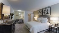 Located at 70 Old Dublin Pike in Doylestown, PA, this two-story property offers a well-designed layout across two floors, blending comfort and functionality in every space. The interior features neutral tones and carpet flooring that create a warm, inviting atmosphere throughout. The primary bedroom is generously sized, showcasing a soft color palette of sage green and warm taupe accent walls complemented by neutral carpeting. A large, upholstered bed serves as the centerpiece, flanked by warm bedside lighting and framed abstract artwork above the headboard. A dedicated sitting and work area with a built-in desk and upholstered chair adds versatility to the room, making it suitable as both a retreat and a workspace. A walk-in closet provides ample storage and organization. The overall ambiance of the home is calm and refined, with consistent design choices that carry through each level. Soft, layered lighting enhances the cozy feel, while the neutral finishes offer a timeless aesthetic. This Doylestown property presents a comfortable and well-maintained living environment within a charming Bucks County setting.