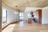 Located at 4845 Chemin de la Côte-Saint-Luc in Montréal, this thoughtfully designed 3-bedroom, 1-bathroom residence offers a compelling blend of industrial character and contemporary finishes. The open-concept living and kitchen area immediately impresses with its signature exposed concrete ceiling, a gracefully curved accent wall, and a striking concrete column that anchors the space. Light hardwood flooring runs throughout, complementing the warm, modern aesthetic.

The kitchen is a standout feature, showcasing rich walnut-toned cabinetry paired with a large central island topped in white quartz with subtle veining. A matching marble-look backsplash, stainless steel appliances, and abundant natural light from expansive windows complete the culinary space, which also offers elevated city views.

The three bedrooms are bright and well-proportioned, with the primary bedroom benefiting from its generous size, exposed concrete ceiling details, and ample closet storage. Additional bedrooms feature large windows framing open city panoramas and exposed structural columns that reinforce the building's architectural identity.

The bathroom is finished with clean, modern lines, featuring a warm wood vanity with a white countertop, a mirrored medicine cabinet, and neutral tile flooring. Four hallways connect the layout fluidly, ensuring a seamless flow throughout this well-appointed Montréal residence.