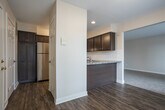 This single-floor residence at 5862 Bayberry Farms Dr SW in Wyoming, Michigan offers a thoughtfully designed layout with a cohesive aesthetic carried throughout. The kitchen serves as a functional centerpiece, featuring rich dark-stained cabinetry, stone-look countertops, a classic white subway tile backsplash, and stainless steel appliances including a gas range and dishwasher. Wood-look flooring runs through the kitchen and connects seamlessly to adjacent areas. The kitchen opens toward a carpeted living area, creating an easy flow between spaces ideal for everyday living. A sliding glass door in one of the carpeted rooms provides direct access to outdoor views of the surrounding green landscape, allowing natural light to fill the space. Additional rooms feature neutral wall tones, plush carpeting, and multiple windows dressed with blinds, offering a bright and comfortable environment. Bedrooms include built-in closets with shelving and hanging rods for practical storage. The bathroom is finished with dark cabinetry matching the kitchen, a stone-look countertop with an undermount sink, wood-look flooring, and clean, neutral walls. Overall, the space presents a consistent, modern design palette with functional finishes throughout.