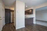 This single-floor residence at 5862 Bayberry Farms Dr SW in Wyoming, Michigan offers a thoughtfully designed layout with a cohesive aesthetic carried throughout. The kitchen serves as a functional centerpiece, featuring rich dark-stained cabinetry, stone-look countertops, a classic white subway tile backsplash, and stainless steel appliances including a gas range and dishwasher. Wood-look flooring runs through the kitchen and connects seamlessly to adjacent areas. The kitchen opens toward a carpeted living area, creating an easy flow between spaces ideal for everyday living. A sliding glass door in one of the carpeted rooms provides direct access to outdoor views of the surrounding green landscape, allowing natural light to fill the space. Additional rooms feature neutral wall tones, plush carpeting, and multiple windows dressed with blinds, offering a bright and comfortable environment. Bedrooms include built-in closets with shelving and hanging rods for practical storage. The bathroom is finished with dark cabinetry matching the kitchen, a stone-look countertop with an undermount sink, wood-look flooring, and clean, neutral walls. Overall, the space presents a consistent, modern design palette with functional finishes throughout.