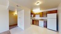 This single-floor residence offers a practical and comfortable layout designed for everyday living. The kitchen is well-equipped with warm oak cabinetry spanning both upper and lower sections, granite-style laminate countertops, a gas range, built-in microwave, dishwasher, and a double-basin stainless steel sink. Light-toned vinyl flooring runs throughout the kitchen, providing easy maintenance and a clean aesthetic.

The living area is generously sized, featuring soft wall-to-wall carpeting and a ceiling fan with integrated lighting. A sliding glass door floods the space with natural light and provides direct access to the outdoors, offering views of the surrounding exterior. The entry door opens directly into this open living space, creating a welcoming flow.

The bedroom continues the carpeted flooring and is fitted with its own ceiling fan, a window that brings in additional natural light, and ample wall space. A closet with paneled double doors provides convenient storage.

The bathroom is clean and functional, featuring a full tub and shower combo, a toilet, and a vanity with a wood cabinet base, granite-style countertop, single sink, and a large mirror above. Light-toned tile flooring completes the space. Throughout the residence, neutral wall tones and consistent finishes create a cohesive, move-in ready environment.