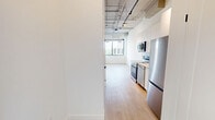 Located at 685 Richmond St in London, Ontario, this 2-bedroom, 1-bathroom unit offers a contemporary loft-inspired design within a compact, efficiently laid-out floor plan. The space features exposed concrete ceilings with industrial-style ducting and track lighting, lending an urban character throughout.

The kitchen is sleek and functional, outfitted with white flat-panel cabinetry, quartz countertops, a textured tile backsplash, and a full suite of stainless steel appliances including a range, over-the-range microwave, dishwasher, and refrigerator. Light hardwood flooring runs seamlessly through the kitchen and into the hallway, connecting the rooms with a warm, cohesive feel.

Both bedrooms are bright and airy, benefiting from large, black-framed windows that invite generous natural light and frame views of the surrounding London cityscape and treetops. The primary bedroom features a double closet with panelled white doors and matte black hardware, adding a refined modern touch.

The bathroom is elegantly finished with large-format stone-look tile lining the walls and a deep soaking tub positioned beneath a window, offering both comfort and natural light. Throughout the unit, clean white walls, minimalist hardware, and quality finishes create a polished, contemporary aesthetic well-suited for urban living.