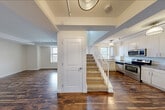 This expansive multi-floor residence offers four bedrooms, three bathrooms, and thoughtfully designed living spaces spread across three levels. The entry level opens into a combined dining and living area characterized by rich, dark hardwood flooring, exposed beam detailing, and track lighting. A staircase with white balustrades connects the levels, and a well-appointed kitchen sits adjacent, featuring light wood cabinetry, granite countertops, stainless steel appliances including a range and built-in microwave, and a window framing city views. The bathrooms are finished with warm tile flooring, modern vanities with clean white countertops, and full bathtub-shower combinations. The upper floors, which comprise the majority of the total footprint, are home to the four bedrooms, all featuring light hardwood floors and windows offering elevated city and treetop views. The generously sized primary bedroom includes two closets and prominent windows that fill the room with natural light. A dedicated walk-in closet with built-in wire shelving provides ample storage. An additional bright, open room on the top floor features a curved wall of windows and access to an outdoor space, adding a distinctive architectural touch to the residence.