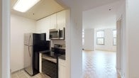 This studio located at 201 Broad St in downtown Stamford, CT offers a well-designed, single-floor layout that maximizes open living space. The main living area is generously proportioned, featuring classic parquet hardwood flooring that adds warmth and character throughout. Multiple windows allow abundant natural light to fill the space while framing views of the surrounding neighborhood, including glimpses of nearby architectural landmarks.

The kitchen is efficiently designed with white upper cabinetry that extends to the ceiling for ample storage, dark granite-style countertops, and a full suite of stainless steel appliances including a refrigerator, electric range, and over-the-range microwave. Tile flooring in the kitchen provides a practical transition from the main living area.

The bathroom is clean and classic in design, featuring white subway-style wall tiles, a pedestal sink with chrome fixtures, and a mirrored medicine cabinet, contributing to a bright and functional space.

A closet provides dedicated storage, and the open layout allows flexible furniture arrangements to suit a variety of living needs. The crisp white walls throughout create a neutral, light-filled ambiance that complements the natural tones of the hardwood floors, resulting in a cohesive and inviting living environment.
