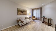 Located at 115 Hutchinson Ave in Columbus, Ohio, this one-bedroom, two-bathroom residence offers a thoughtfully designed single-floor layout with a cohesive, contemporary aesthetic. The open-concept living and kitchen area serves as the heart of the home, featuring light wood-style flooring that extends throughout the main living spaces, neutral wall tones, and sheer curtains that allow natural light to filter in. The kitchen is well-appointed with warm wood cabinetry featuring frosted glass inserts, stainless steel appliances including a full-size refrigerator and microwave, a subway tile backsplash, and light countertops — offering both functionality and style. The living area provides a comfortable, welcoming atmosphere with ample room for seating and entertainment. The bedroom is a restful retreat, showcasing patterned carpet, a bold accent wall in deep gray, and a dedicated closet. A hallway bathroom features granite-topped wood vanity cabinetry, a tub-shower combination, and tile flooring, while a second bathroom off the bedroom corridor includes a backlit vanity mirror and additional vanity storage. A utility room rounds out the floor plan. Throughout, textured ceilings, recessed lighting, and warm finishes contribute to a clean, modern ambiance.