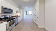 Located at 370 Asylum St in downtown Hartford, Connecticut, this efficiently designed single-floor unit offers a thoughtfully utilized layout across its two main areas. The open-concept living and kitchen space is bright and contemporary, featuring light wood-style flooring that runs continuously throughout, crisp white walls, and a large window that draws in natural light while framing views of the surrounding urban streetscape.

The kitchen is well-appointed with white flat-front cabinetry extending to the ceiling for ample storage, dark countertops, and a full suite of stainless steel appliances including a refrigerator, electric range, over-the-range microwave, and dishwasher. A stainless steel sink with a modern faucet completes the functional cooking area. The kitchen flows seamlessly into the open living space, which is clean and versatile, offering a blank canvas for various furniture arrangements.

The bathroom is finished in a modern style, featuring gray shaker-style vanity cabinetry, a white quartz countertop, a recessed medicine cabinet mirror, and a full tub-shower combination with white subway tile surround and chrome fixtures. The overall design aesthetic throughout is clean, minimal, and move-in ready, making this a practical urban residence in the heart of Hartford.