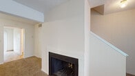 This two-floor home offers a well-organized layout designed for comfortable everyday living. The main living area is anchored by a wood-burning fireplace with a white-painted surround, set against neutral-toned walls and wall-to-wall carpeting that extends throughout the living and bedroom spaces. A staircase connects the two floors, adding a sense of vertical openness to the layout.

The kitchen is equipped with ample white cabinetry, a double-basin sink, a built-in dishwasher, and an electric range, all set atop tile flooring that carries through into the adjacent areas. The layout is efficient and practical, offering generous counter space for meal preparation.

The bedrooms are bright and generously sized, each featuring plush carpeting, neutral walls, and windows that allow natural light to fill the rooms. The textured ceilings are consistent throughout the home, lending a classic character to each space.

Two bathrooms serve the home, both featuring tile flooring, vanities with built-in storage, and clean, functional fixtures. One bathroom includes a full tub and shower combination, while the other provides a convenient half-bath configuration. Throughout the home, the light, neutral color palette and practical finishes create a clean and inviting atmosphere ready for personal customization.