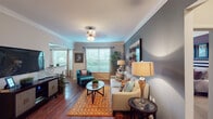 Located at 9611 Grant Rd in Houston, TX 77070, this thoughtfully designed single-floor residence offers a cohesive blend of comfort and style throughout its well-planned layout. The open living area is anchored by rich hardwood-style flooring, crown molding, and a neutral palette accented by a bold slate-blue feature wall. Multiple windows dressed with blinds and curtains invite abundant natural light while offering outdoor views of the surrounding greenery. The kitchen is outfitted with warm wood cabinetry, a mosaic tile backsplash, stainless steel appliances including a range, microwave, and dishwasher, and a black refrigerator — all centered around a functional layout ideal for everyday cooking. Adjacent to the living room, a dedicated dining area features a bay-style window arrangement that frames outdoor views, creating a bright and welcoming space for meals. The bedroom is a serene retreat with plush carpeting, a ceiling fan, and generous natural light, complemented by a spacious walk-in closet with wire shelving. The bathroom features a deep-toned accent wall, a single-sink vanity with a wide mirror, and a shower-tub combination. A dedicated laundry area with a full-size washer and dryer adds everyday convenience to this well-rounded residence.