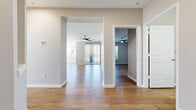 Located in Parker, Colorado, this single-floor, 2-bedroom, 2-bathroom residence offers a well-designed open-concept layout with consistent hardwood-style flooring throughout. The kitchen is a functional centerpiece, featuring white shaker cabinetry, a peninsula island with a breakfast bar, stainless steel appliances including a full-size refrigerator, a black range, and a dishwasher, all complemented by light countertops and a window that fills the space with natural light. The kitchen flows seamlessly into the living area, which is equipped with a ceiling fan and access to a private balcony via sliding glass doors. Both bedrooms are generously sized, with the primary bedroom offering crown molding, a ceiling fan, balcony access, and a walk-in closet with wire shelving. The second bedroom is bright and open, connected to the hallway. Two full bathrooms include white cabinetry, tile surround tub-shower combos, and hardwood-style flooring. A dedicated in-unit laundry room houses a full-size side-by-side washer and dryer with overhead wire shelving for added storage. The neutral color palette and clean finishes throughout create a bright, move-in-ready atmosphere.