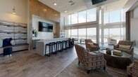 Located at 10 Westedge St in Charleston, SC, this stunning amenity floor showcases a refined blend of contemporary design and upscale functionality. Dramatic double-height ceilings and expansive floor-to-ceiling windows define the space, flooding every area with natural light and framing sweeping panoramic views of the Charleston waterfront and surrounding cityscape.

The open-plan social lounge serves as a central hub, featuring a sleek bar with counter seating, a wall-mounted television, and a generous seating area with plush armchairs arranged to take full advantage of the breathtaking views. Adjacent to the lounge, a spacious dining area accommodates large gatherings around a long communal table beneath a modern rectangular chandelier. The striking herringbone-patterned tile floor adds a dynamic visual element to this entertaining zone.

A dedicated coffee and refreshment station, finished with mosaic tile backsplash and gray cabinetry, provides a convenient amenity for daily use. A cozy lounge nook with soft blue walls and comfortable seating offers a quieter retreat for relaxation or casual viewing.

The recreation room features a pool table, built-in teal shelving, and a mounted television, creating a lively game area. A conference-style dining room with direct balcony access provides an ideal setting for meetings or events, with outdoor terrace space offering additional al fresco seating with panoramic views.