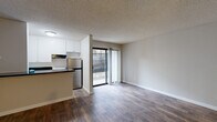 Located at 2185 Chatsworth Blvd in San Diego's Point Loma neighborhood (92107), this efficiently designed single-floor unit makes smart use of its compact footprint. The open-concept layout seamlessly combines the living room, dining area, and kitchen into one cohesive space, promoting an airy, connected feel throughout.

The kitchen features white upper cabinetry, dark countertops, stainless steel appliances, and a peninsula that provides both workspace and a natural divider between the kitchen and living areas. Rich wood-look flooring runs throughout the main living spaces, adding warmth and visual continuity. A textured ceiling adds architectural character overhead. A sliding glass door floods the living area with natural light and opens directly onto a private patio space.

A hallway connects the main living area to the rest of the unit, which includes a closet for storage and two bathrooms. The bathrooms are finished with light wood-look flooring, white cabinetry, dark speckled countertops, and mirrored medicine cabinets, offering a clean and functional aesthetic. The overall color palette of neutral grays and whites throughout the unit creates a calm, cohesive atmosphere well-suited to everyday living.