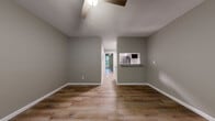 Located at 550 S Laclede St in Wichita, Kansas, this single-floor home has been thoughtfully updated with modern finishes and a clean, cohesive aesthetic. Warm wood-look luxury vinyl plank flooring runs throughout the entire space, complemented by neutral gray walls and crisp white baseboards that create a bright, contemporary feel.

The living area is open and welcoming, featuring a ceiling fan with light fixture and a textured ceiling. A convenient pass-through window connects the living space directly to the kitchen, enhancing the open flow between rooms. The kitchen is well-appointed with stainless steel appliances — including a refrigerator, gas range, and over-the-range microwave — white cabinetry, granite-look countertops, and a classic white subway tile backsplash.

The bedrooms are comfortably sized, each featuring ceiling fans, wood-look flooring, and windows with blinds that bring in natural light. The bathroom is clean and functional, outfitted with white cabinetry, a full tub-shower combo with white surround, and matching hardware throughout.

Additional features include a wall-mounted PTAC heating and cooling unit, a front entry door with a keypad lock, and a practical hallway connecting the main living areas to the private rooms. The home presents a move-in-ready condition with modern updates throughout.