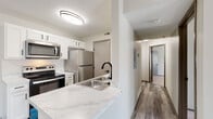 Located at 5400 Diamond Loch in Columbus, Ohio, this single-floor unit offers a clean, modern aesthetic throughout. The open-concept kitchen is a standout feature, showcasing white shaker cabinetry with matte black hardware, marble-look countertops, a peninsula with an undermount double sink and matching black faucet, and a full suite of stainless steel appliances including a range, over-the-range microwave, and refrigerator. Light gray wood-look flooring runs throughout the main living areas, providing a cohesive and contemporary feel. The living area is bright and airy, with natural light flowing in through windows with blinds. The bedrooms are carpeted for comfort and feature neutral tones, textured ceilings, and generous windows that invite natural light. At least one bedroom includes a spacious walk-in closet equipped with wire shelving and hanging rods, offering substantial storage capacity. The bathroom is neatly finished with a white vanity, a tub-shower combination, and coordinating black hardware accents. The overall design emphasizes clean lines, neutral tones, and functional updates, making this a well-maintained and move-in-ready space in the Columbus, OH area.