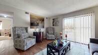 Located at 3607 W 13th St N in Wichita, Kansas, this single-story home offers three bedrooms and one bathroom within a efficiently organized floor plan. The layout is connected by a central hallway that provides straightforward access to each room.

The living room serves as the heart of the home, featuring hardwood-style flooring and a textured ceiling. A large sliding glass door with vertical blinds fills the space with natural light while offering outdoor views. The room comfortably accommodates seating and a coffee table arrangement.

The galley-style kitchen is outfitted with dark cabinetry, white countertops, a double-basin sink, and tile flooring. A range and dishwasher are included, with under-cabinet lighting adding functional illumination.

The spacious primary bedroom features carpet flooring and a closet with louvered bifold doors. The two additional bedrooms are also carpeted and include closet storage, with one bedroom featuring a window that brings in natural light.

The bathroom includes a full tub-and-shower combination with white tile surround accented by decorative tile inserts. A carpeted closet in the hallway provides additional storage with a built-in hanging rod.