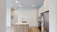 Located at 2255 E Fairview Ave in Meridian, Idaho, this single-floor unit offers a thoughtfully designed layout with a cohesive modern aesthetic throughout. The interior is defined by light-toned hardwood-style flooring that runs continuously across the living areas, bedrooms, and bathroom, lending warmth and visual continuity to the space.

The kitchen serves as a central feature, anchored by a peninsula island with an undermount sink, brushed nickel pull-down faucet, and smooth light wood cabinetry that extends to the ceiling for ample storage. Stainless steel appliances—including a refrigerator, electric range, and over-the-range microwave—complement the white tile backsplash and clean countertops, creating a polished, functional cooking space.

The living area flows openly from the kitchen, with recessed lighting and a ceiling fan providing both ambiance and comfort. Bedrooms are bright and airy, each benefiting from large windows that invite natural light and offer views of surrounding greenery and the neighborhood.

The bathroom features a wide-format vanity mirror, light wood cabinetry with drawer storage, an undermount sink with quartz-style countertop, and a shower-tub combination. A dedicated in-unit laundry closet houses a stacked Whirlpool washer and dryer with overhead shelving. The overall ambiance is clean, minimal, and move-in ready.