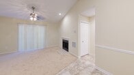 This two-bedroom, two-bathroom single-floor residence at 2528 Potomac Hunt Ln in Henrico, Virginia offers a well-organized layout with a cohesive, neutral design throughout. The living room serves as the centerpiece of the home, featuring vaulted ceilings, a ceiling fan, recessed lighting, a tile-surround fireplace, and access to a sliding glass door dressed with vertical blinds, allowing for natural light. Soft carpeting and light tile flooring carry through the common areas, lending a warm, comfortable feel. The galley-style kitchen is efficiently laid out with warm wood cabinetry, light granite-style countertops, tile flooring, and black appliances including a range, refrigerator, and dishwasher. Both bedrooms are carpeted and finished in soft yellow tones, each offering generous window coverage with horizontal blinds that invite natural light. The primary bedroom includes direct access to a hallway leading to the adjoining bath. The two bathrooms include a full bath with a tiled tub-shower combination and a second full bath featuring a wood vanity with a white countertop, large mirror, tile flooring, and a tub-shower. Hallways and a closet add functional storage and connectivity throughout this efficiently designed home.